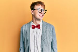 young adult with autism wears a bow tie and glasses and looks away from the camera. He gets online autism therapy in California with an autism therapist from Open Doors Therapy