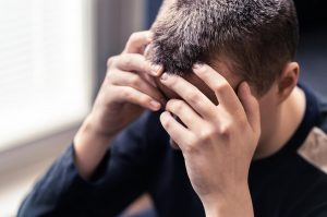 man with his hands on his head looking distressed. To become more self-aware he could begin autism therapy in California or autism group therapy with an autism therapist at Open Doors Therapy. 
