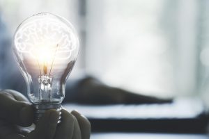 image of a person holding a lightbulb with a brain inside representing thought and innovation. Learn more about autism therapy and finding your strengths from an autism therapist in Palo Alto, CA and an online autism therapist in California at Open Doors Therapy